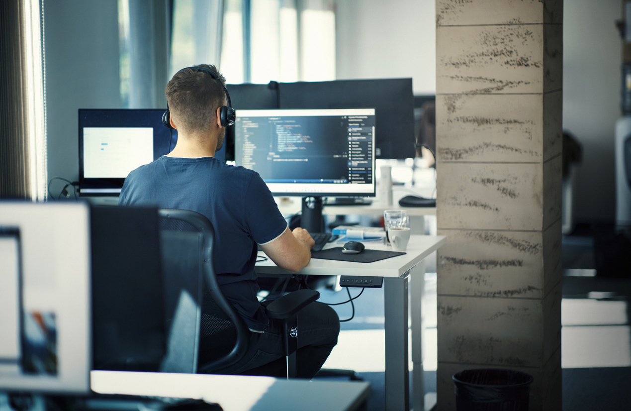 Tecnico IT al lavoro su codice in un ufficio moderno, sviluppo software e supporto Cloud